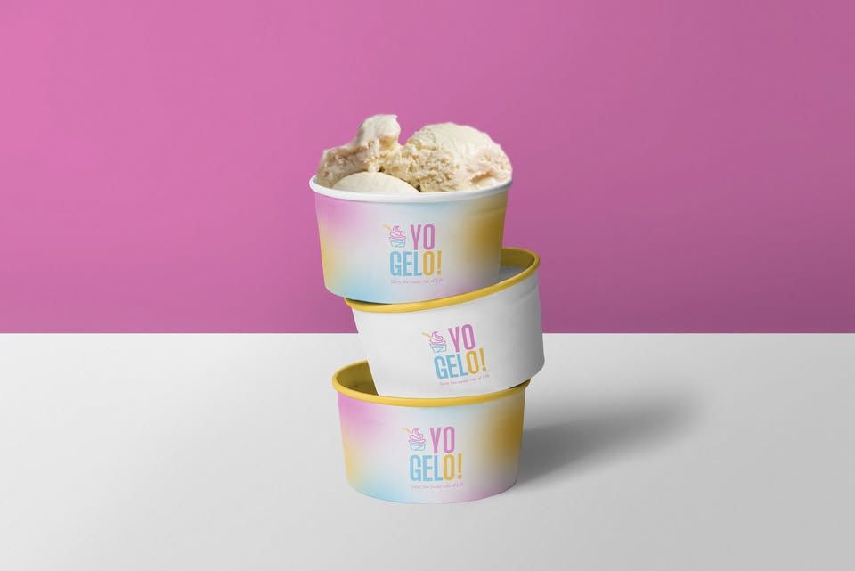 Three Yogelo cups stacked on a magenta wall, the top one filled with gelato